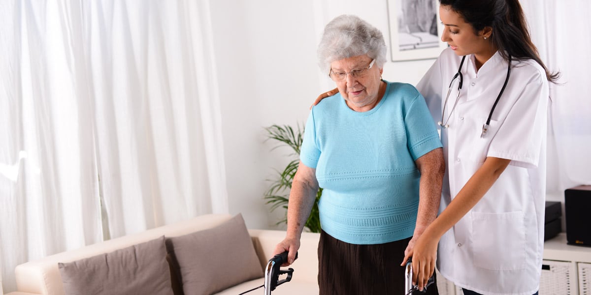 nurse helping senior woman with walker