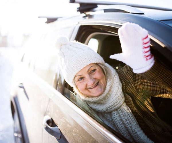 senior woman in winter clothing in car